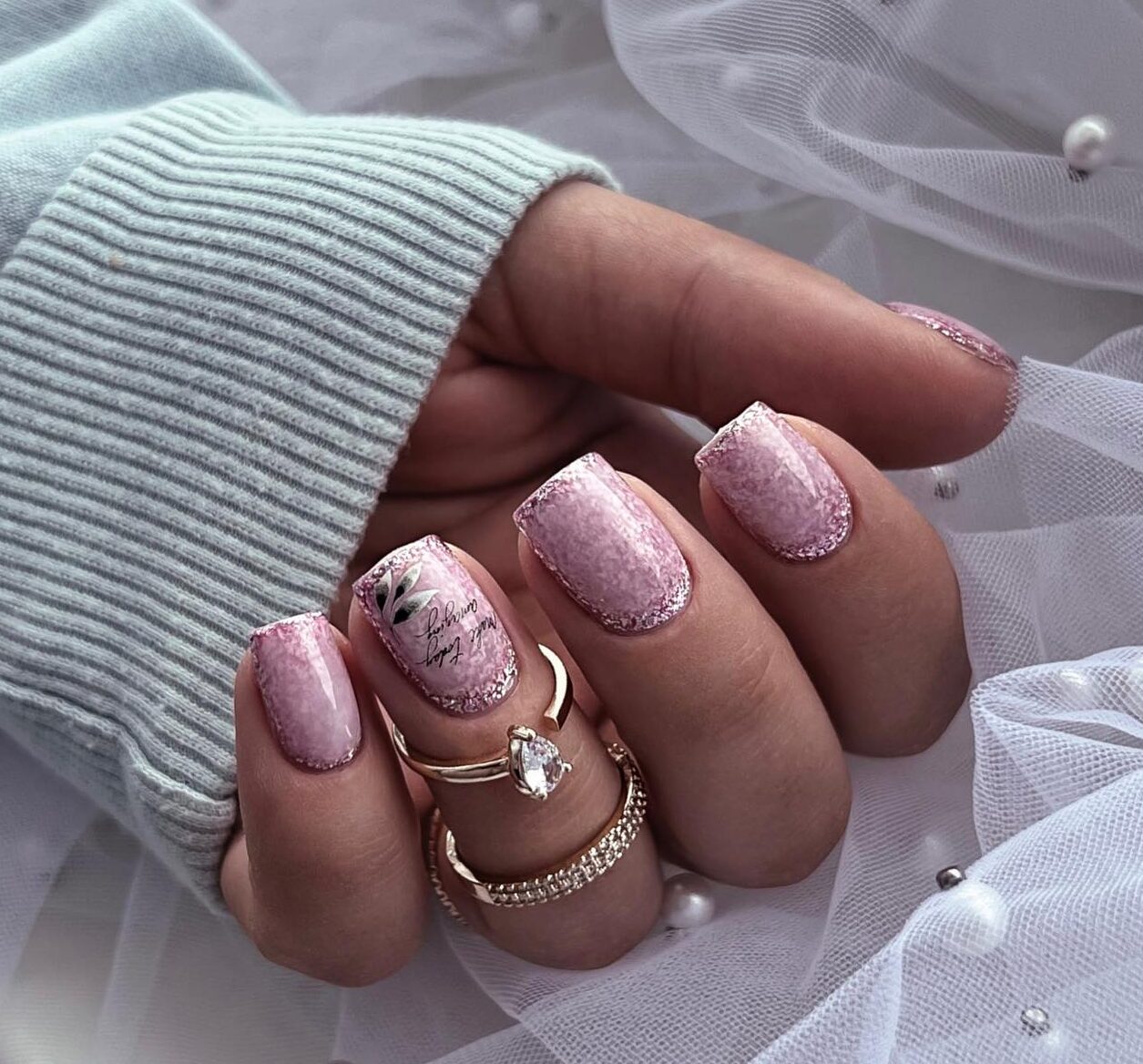 Esmalte de uñas de oro rosa con arte abstracto en uñas cortas y cuadradas.