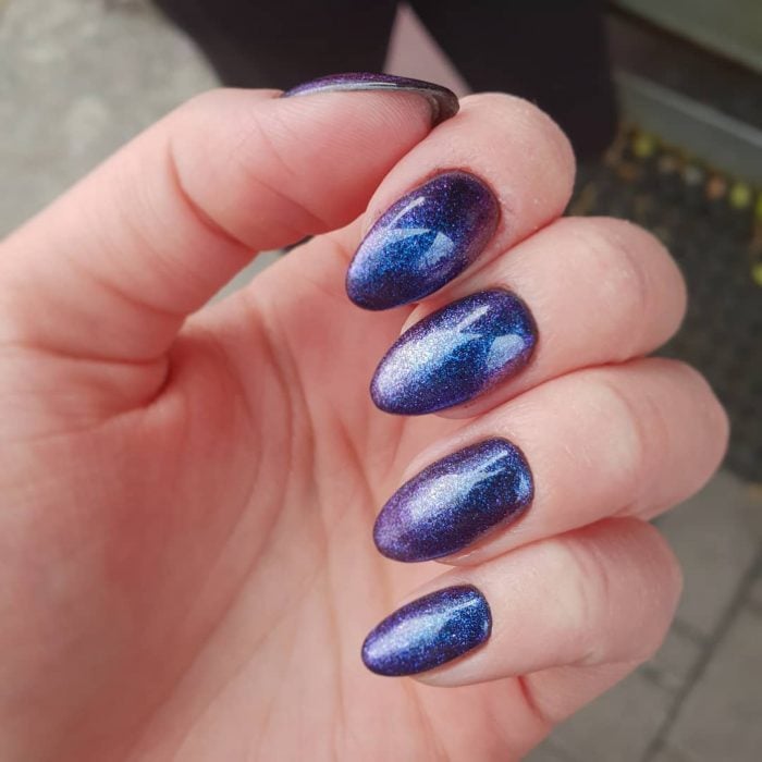 manos de mujer con uñas color azul metálico