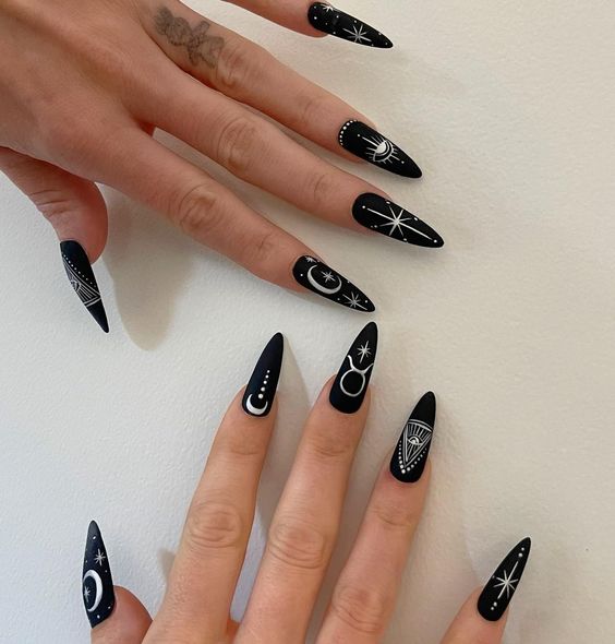 Color de uñas negro intenso con acabado mate con el signo de Tauro blanco y elementos celestiales en uñas largas estilo stiletto