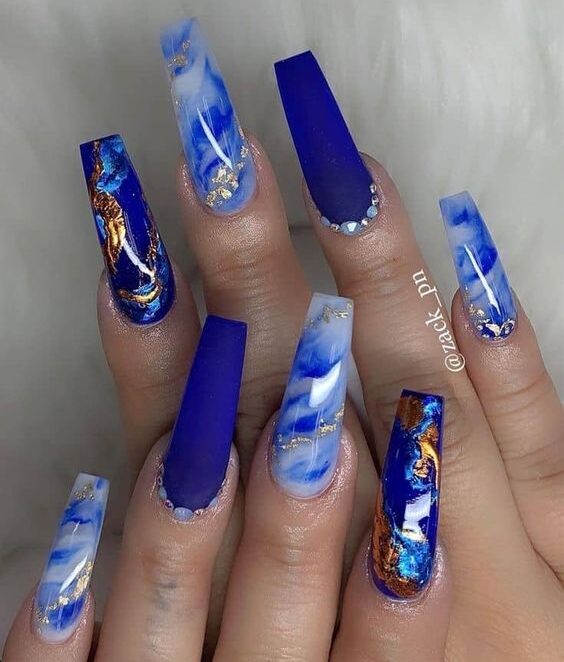 Esmalte de uñas azul real con decoración de uñas de mármol y lámina dorada en uñas largas de ataúd