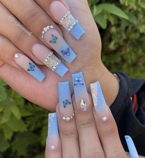 Arte de uñas ombre azul bebé con mariposas azules y piedras en uñas largas y cuadradas