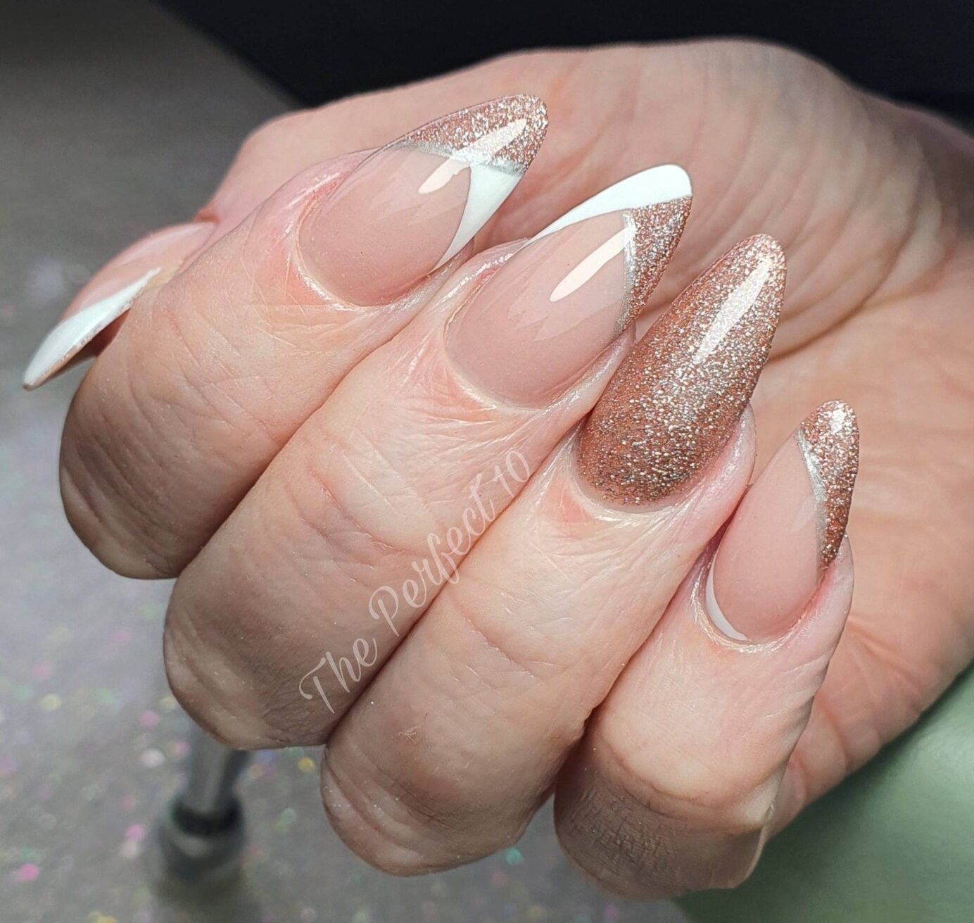 Combinación de puntas francesas brillantes en oro rosa y blanco en uñas medianas almendradas