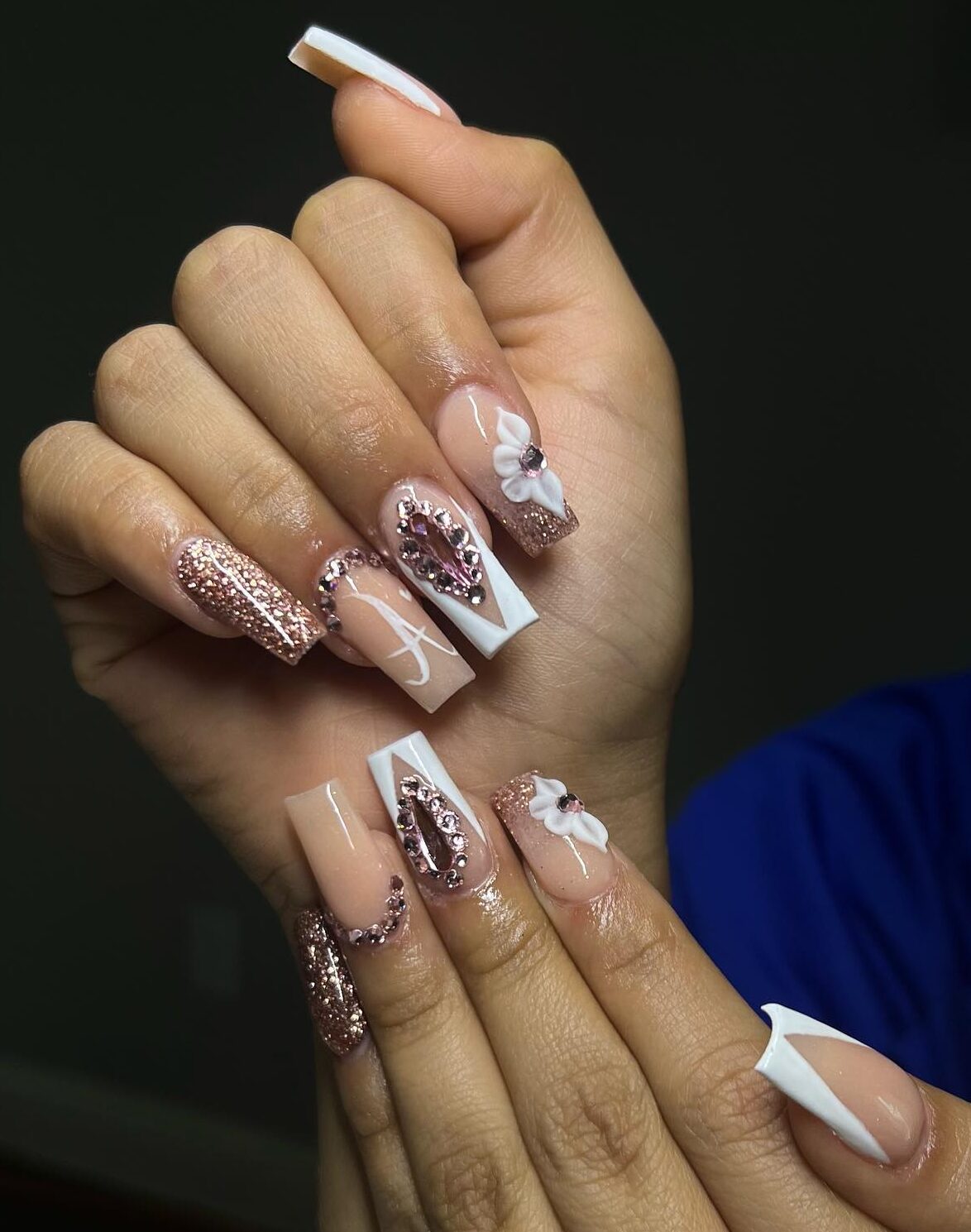 Uñas acrílicas largas y cuadradas con puntas francesas en oro rosa y blanco, pedrería y flores en 3D.