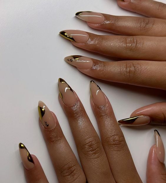 Arte de uñas abstracto en oro brillante sobre uñas acrílicas largas en forma de aguja