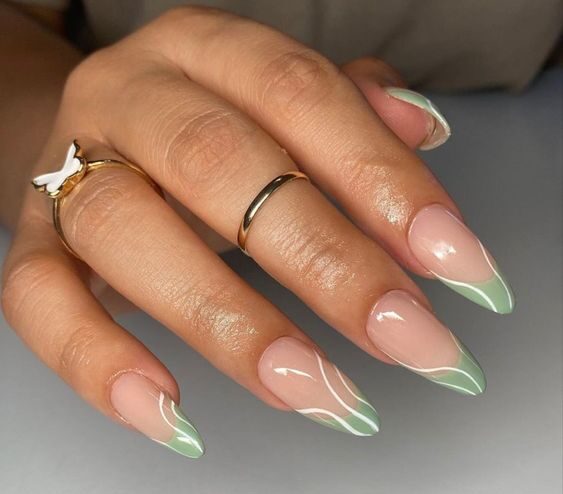 Puntas francesas de color verde salvia con patrones arremolinados en uñas acrílicas largas con forma de almendra