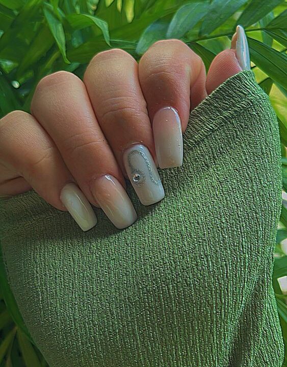 Esmalte de uñas verde salvia con arte de uñas minimalista del signo Leo en uñas acrílicas largas y cónicas de forma cuadrada