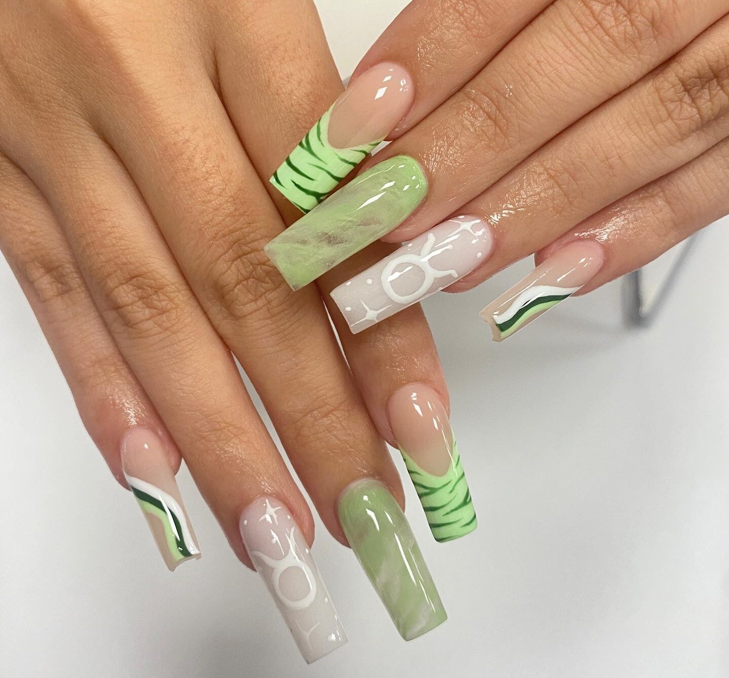 Puntas francesas de color verde claro, remolinos y diseños de uñas de mármol con el signo de Tauro en uñas acrílicas largas y cuadradas.