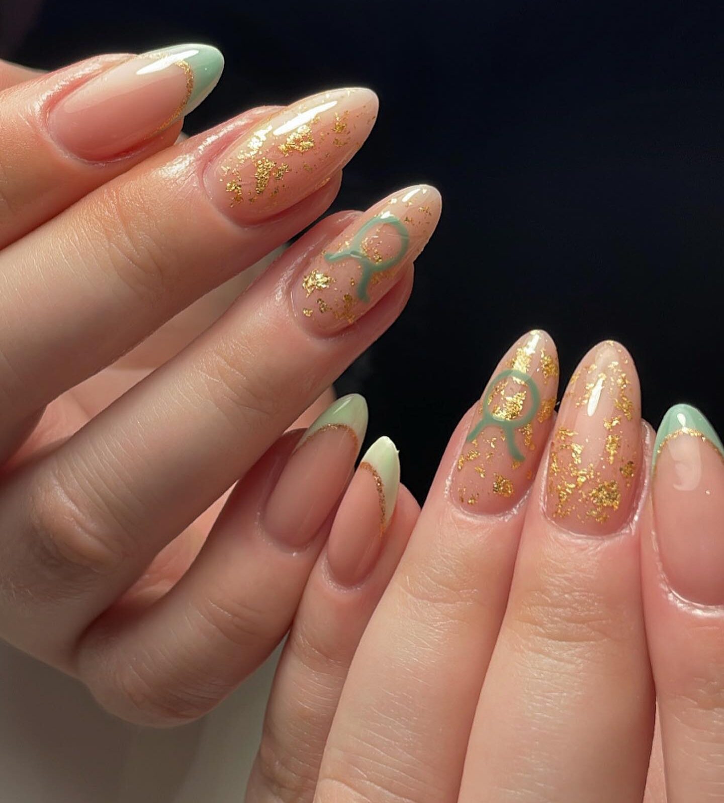 Puntas francesas de color verde pálido, detalles en láminas doradas y diseños de uñas con el signo de Tauro en uñas largas color almendra