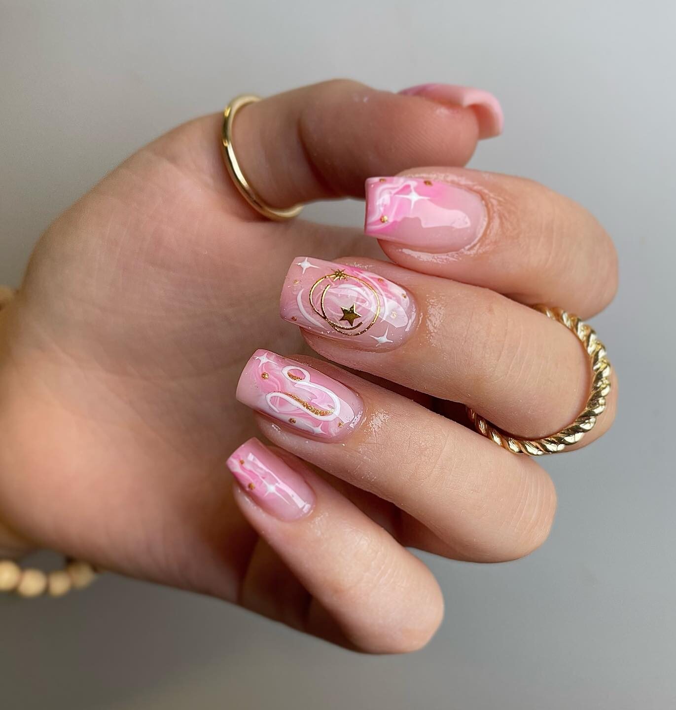 Mármol rosado ahumado con arte de uñas con el signo de Leo en uñas transparentes cuadradas de punta media y cónica