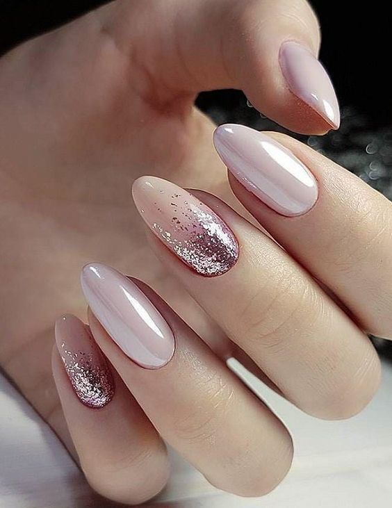 Esmalte de uñas rosa pálido brillante con brillos rosados ​​en uñas redondas medianas