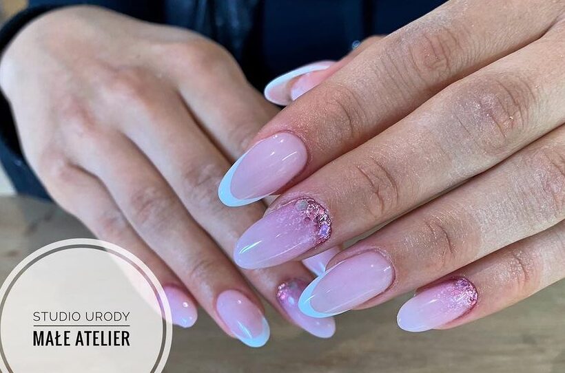 Uñas redondas lisas con puntas francesas blancas y brillos de oro rosa.