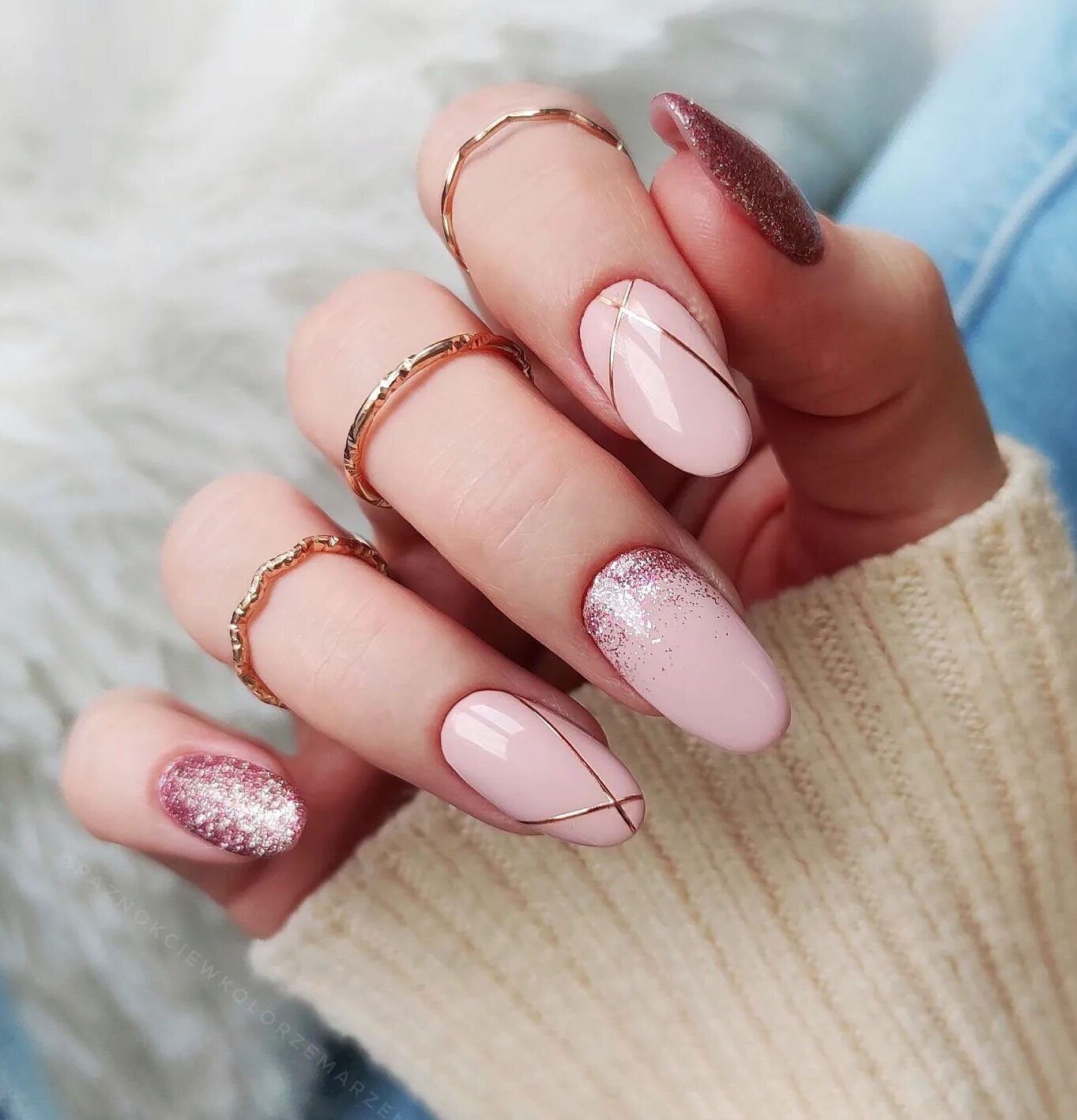 Esmalte de uñas rosa claro con líneas de oro rosa y brillos de oro rosa en uñas medianas y redondas