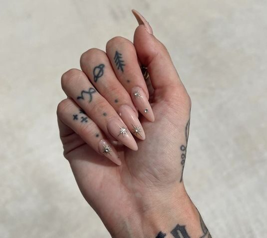 Color de uñas nude con diseños minimalistas de uñas celestiales en uñas acrílicas largas con forma de almendra