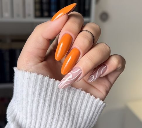 Esmalte de uñas naranja y remolinos blancos en uñas largas y redondas