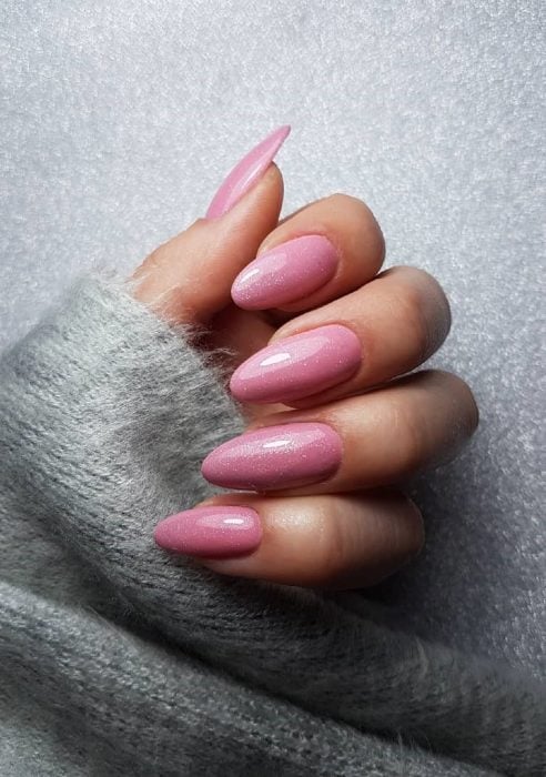 manos de mujer con uñas color rosa