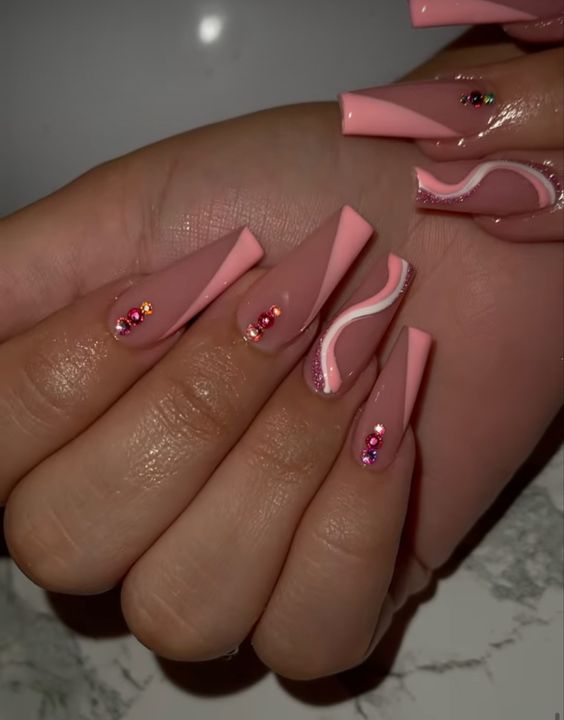 Puntas francesas inclinadas de color rosa bebé y remolinos con pedrería rosa en uñas acrílicas largas con forma de ataúd