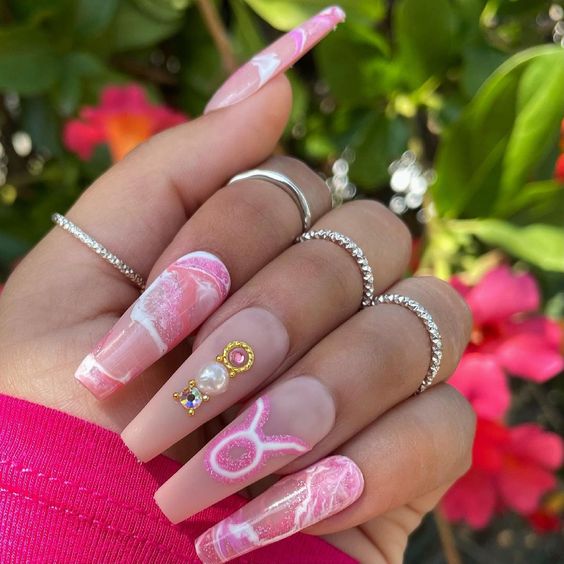Color de uñas nude con decoración de uñas de mármol rosa y signo de Tauro en uñas acrílicas largas con forma de ataúd