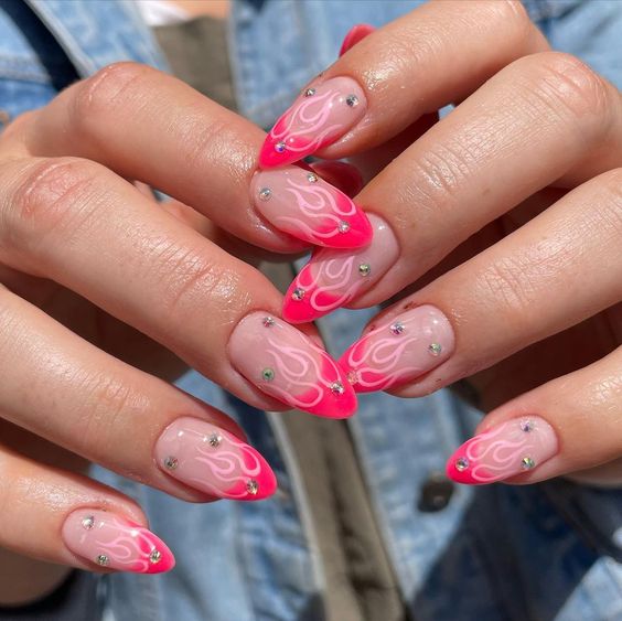 Esmalte de uñas de color beige con puntas francesas de color rosa neón, llamas de color rosa claro y pedrería en uñas largas color almendra.
