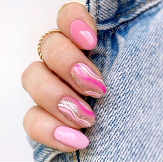 Remolinos de color rosa claro y dorado en uñas redondas medianas.
