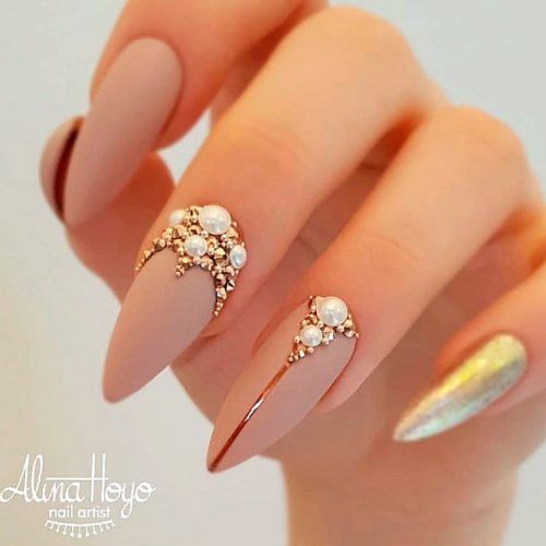 Esmalte de uñas marrón nude con acabado mate con perlas y bling en uñas largas stiletto