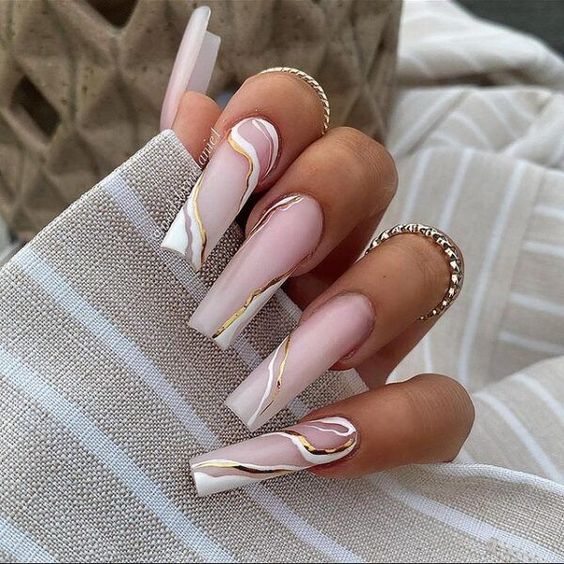 Uñas acrílicas blancas transparentes con remolinos blancos y dorados.