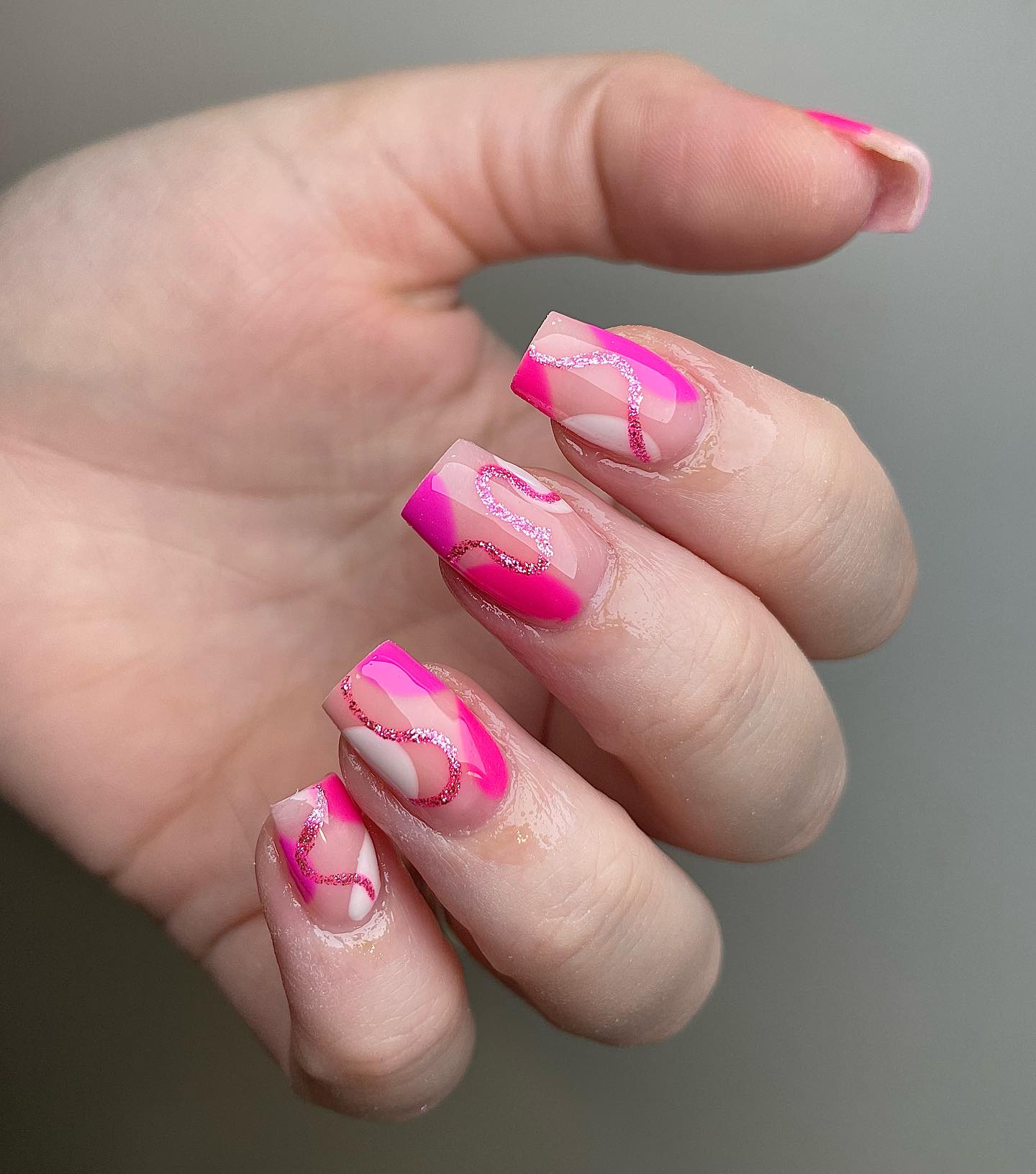 Arte de uñas abstracto en rosa y blanco con patrones arremolinados en uñas cuadradas de punta media y cónica