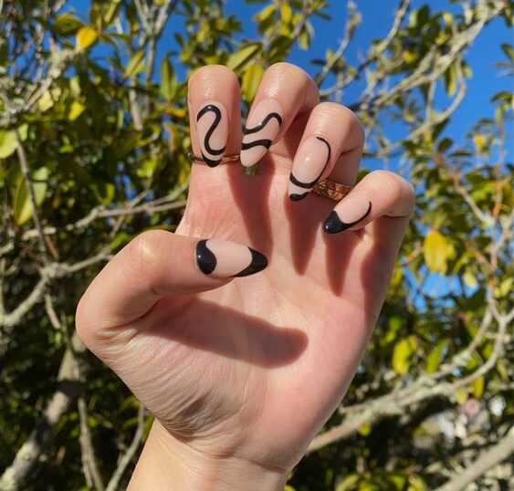 Arte de uñas en forma de remolino abstracto negro en uñas acrílicas largas con forma de almendra