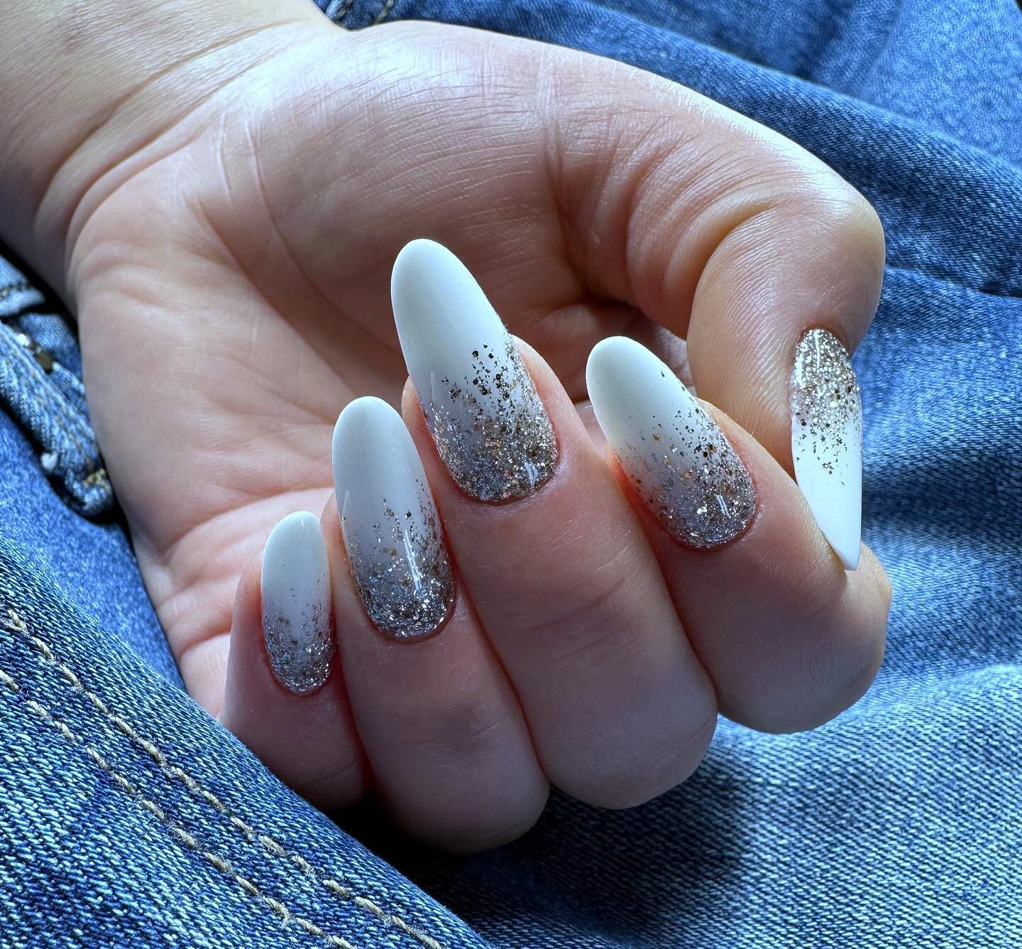Esmalte de uñas blanco con diseño de uñas con brillos plateados en uñas largas y redondas