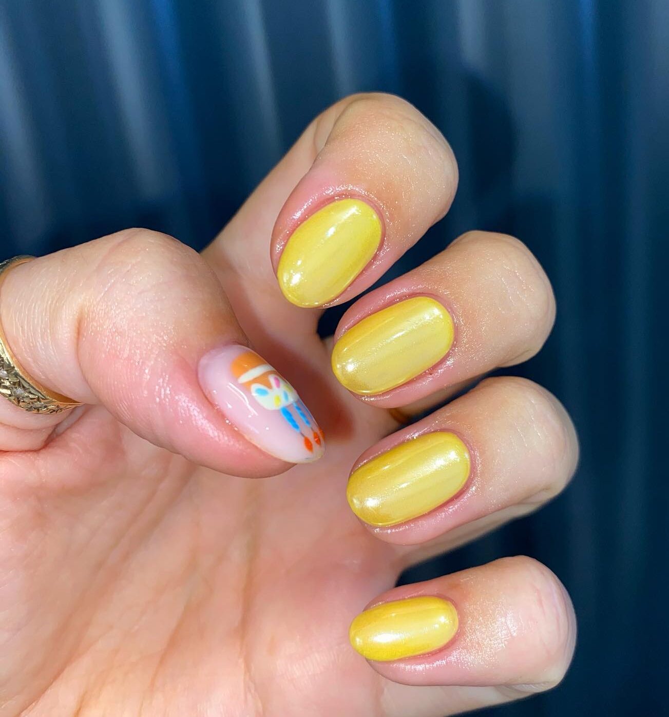 Esmalte de uñas amarillo con acabado brillante en uñas cortas y redondas.