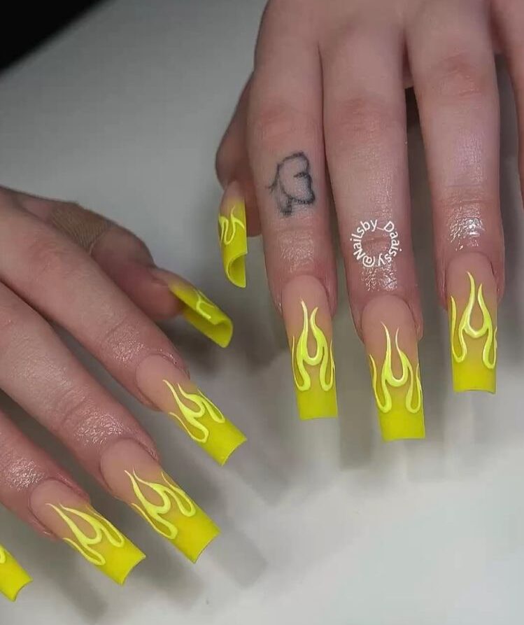 Arte de uñas con llamas de color amarillo brillante en uñas acrílicas largas y cuadradas