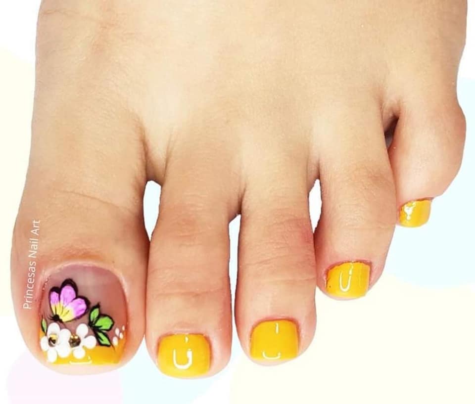 Nail Unas de Pies pintadas de amarillo con mariposa rosa y flores verdes en dedo mayor