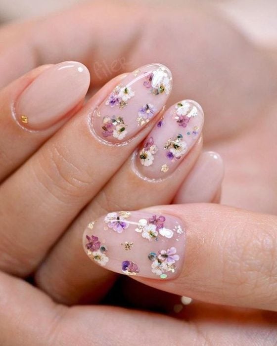 Mujer con manicura de flores lilas en miniatura