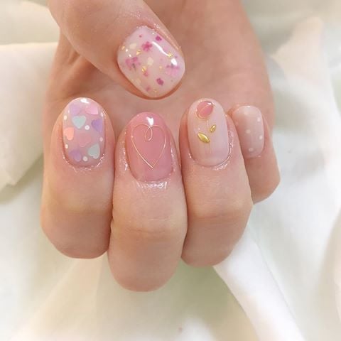 Manicura en tono rosa pastel con pequeñas flores rosas y doradas