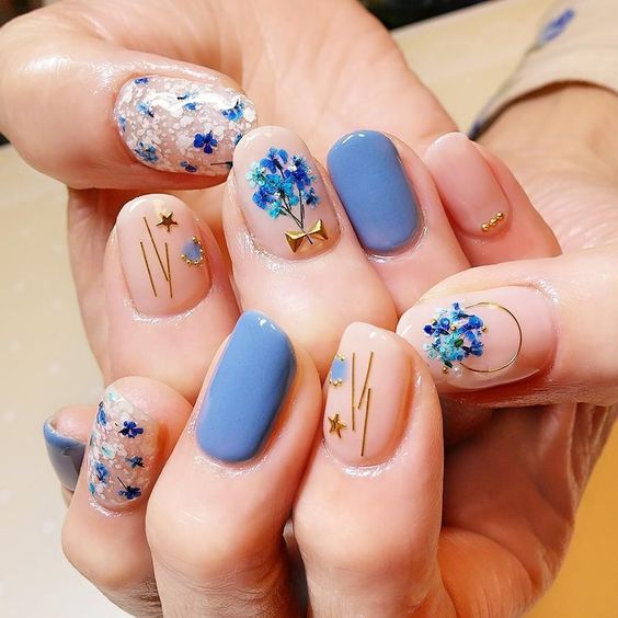 Manicura en tono azul cielo con flores doradas