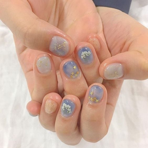 Manicura en tono azul cielo con flores blancas y doradas